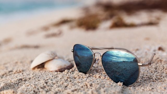 Closeup Of Blue Sunglasses On The Tropical Beach